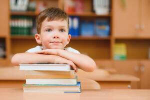 Portrait of cute boy on top of book stack. The concept of learning in primary school. photo