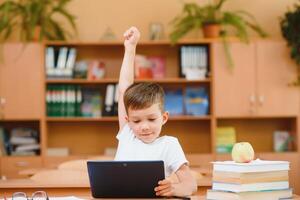 Elementary schoolboy using digital tablet with classmate studying in background at classroom photo