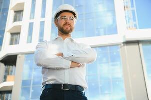 Portrait of man engineer at building site. Male construction manager wearing white helmet and yellow safety vest photo