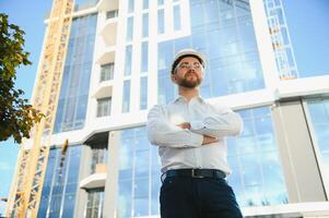 Portrait of man engineer at building site. Male construction manager wearing white helmet and yellow safety vest photo