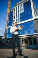 Architect in helmet writing something near new building photo