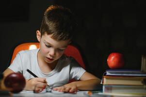 Boy learn lessons in the home setting at the table in the light of a table lamp. photo