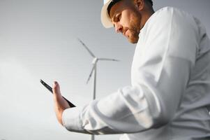 Electrical engineers working at wind turbine power generator station with laptop computer photo