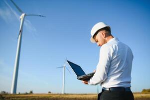 Engineer standing and hoding laptop with wind turbine. photo