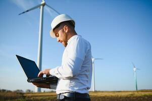 Engineer standing and hoding laptop with wind turbine. photo