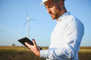Electrical engineers working at wind turbine power generator station with laptop computer photo