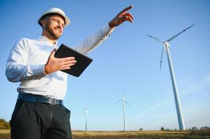 Electrical engineers working at wind turbine power generator station with laptop computer photo