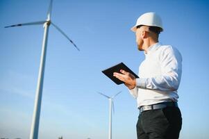 Electrical engineers working at wind turbine power generator station with laptop computer photo