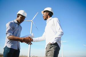 Young maintenance engineer team working in wind turbine farm at sunset stock photo