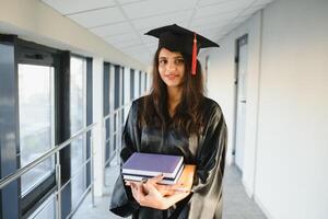 Happy Indian university student in graduation gown and cap holding diploma certificate. photo