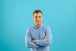 Happy smiling handsome man in clothing, showing copy space, visual imaginary or something, or pressing virtual button, aqua marine blue color background. photo