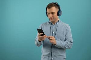 Handsome young man posing on color background. Young smiling man listening to music on headphones. photo