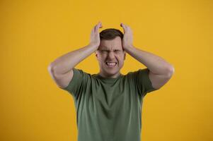Portrait of a young man holding his head with his hands. Concept of despair and hopelessness. Frustration. Migraine photo