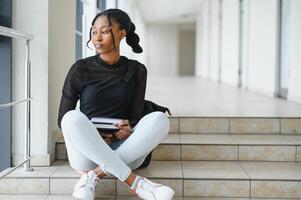 Happy smiling african-american student girl with backpack at university background. Technology, education, leisure concept photo