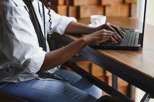 Cropped image of Afro American girl drinking coffee while working with a laptop in cafe photo