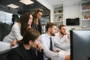 Smiling business people sitting at a desk in front of a laptop computer photo