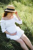 Beautiful pregnant woman relaxing outside in the park photo