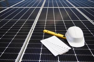 Solar cell contractor document with orange engineering team helmet on solar cells panels. Renewable energy and ecology concept. photo