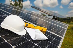 Solar cell contractor document with orange engineering team helmet on solar cells panels. Renewable energy and ecology concept. photo