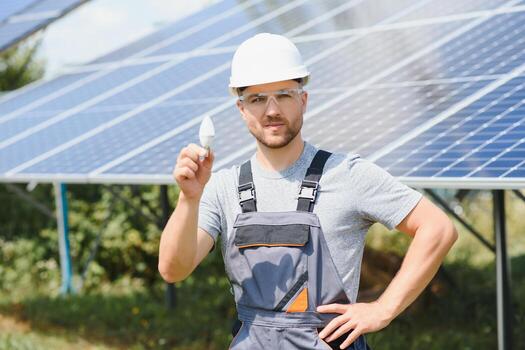 Technical expert in solar photovoltaic panels, remote control performs routine actions to monitor the system using clean renewable energy in the hand a light bulb. photo