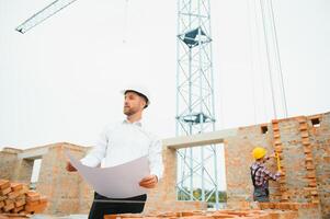 Engineering Consulting People on construction site holding blueprint in his hand. Building inspector. Construction site check drawing and business workflow of new building. photo
