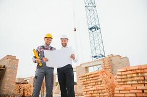 engineer and builder in hard hats discussing blueprint on construction site. photo