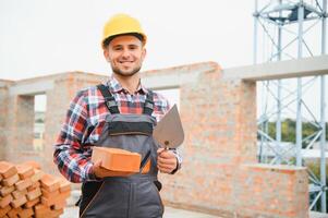 Busy with brick wall. Construction worker in uniform and safety equipment have job on building. photo