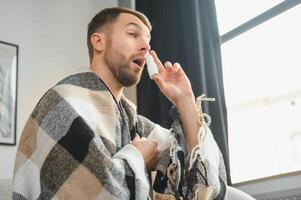 Sick man with nasal spray and paper tissue at home photo