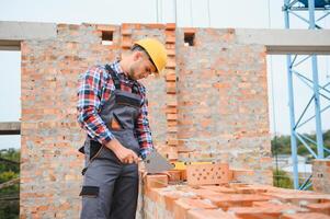 Installing brick wall. Construction worker in uniform and safety equipment have job on building photo