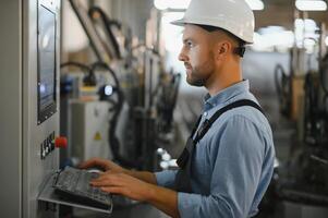 Portrait of factory worker in protective uniform and hardhat standing by industrial machine at production line. People working in industry photo
