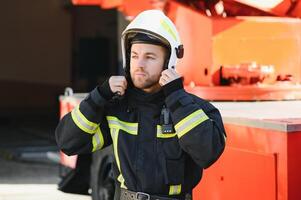 Firefighter portrait on duty. Photo fireman with gas mask and helmet near fire engine.