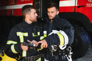 Portrait of two firefighters in fire fighting operation, fireman in protective clothing and helmet using tablet computer in action fighting photo
