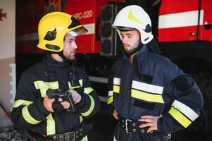 Portrait of two firefighters in fire fighting operation, fireman in protective clothing and helmet using tablet computer in action fighting photo