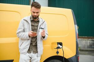 Man charging electric car by the work photo