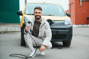 Man charging electric car by the work photo