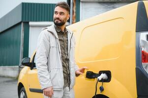 Man charging electric car by the work photo