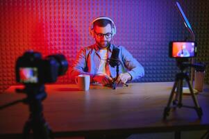 vlogger using smartphone to film podcast in studio. blogger with mobile phone, microphone and headphones filming for social media broadcasting career. photo