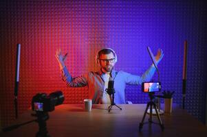 Young man recording or streaming podcast using microphone at his small broadcast studio. Content creator. photo