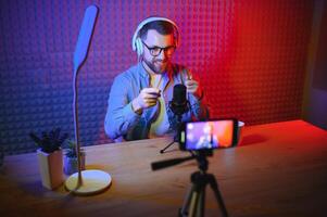 vlogger using smartphone to film podcast in studio. blogger with mobile phone, microphone and headphones filming for social media broadcasting career. photo