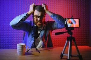 Young man recording or streaming podcast using microphone at his small broadcast studio. Content creator. photo
