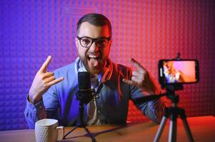 Young man recording or streaming podcast using microphone at his small broadcast studio. Content creator. photo