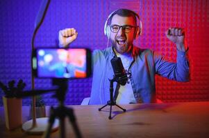 vlogger using smartphone to film podcast in studio. blogger with mobile phone, microphone and headphones filming for social media broadcasting career. photo
