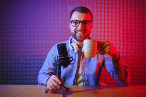 Young man recording or streaming podcast using microphone at his small broadcast studio. Content creator. photo