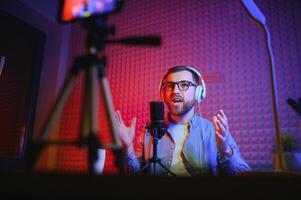 Young man recording or streaming podcast using microphone at his small broadcast studio. Content creator. photo