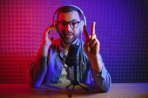 vlogger using smartphone to film podcast in studio. blogger with mobile phone, microphone and headphones filming for social media broadcasting career. photo