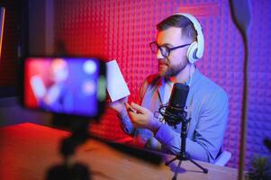 vlogger using smartphone to film podcast in studio. blogger with mobile phone, microphone and headphones filming for social media broadcasting career. photo