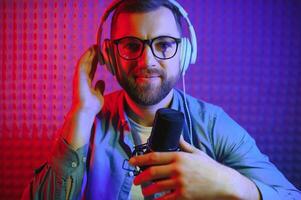 Young man recording or streaming podcast using microphone at his small broadcast studio. Content creator. photo