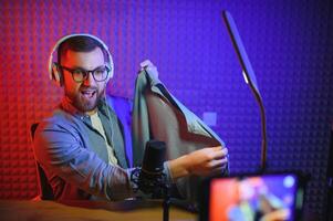 Young man recording or streaming podcast using microphone at his small broadcast studio. Content creator. photo