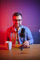 vlogger using smartphone to film podcast in studio. blogger with mobile phone, microphone and headphones filming for social media broadcasting career. photo