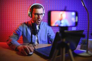 Young man recording or streaming podcast using microphone at his small broadcast studio. Content creator. photo